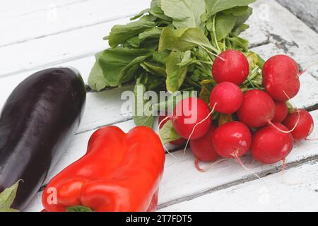 Radieschen, roter Pfeffer, Auberginen auf einem weißen Tisch Stockfoto