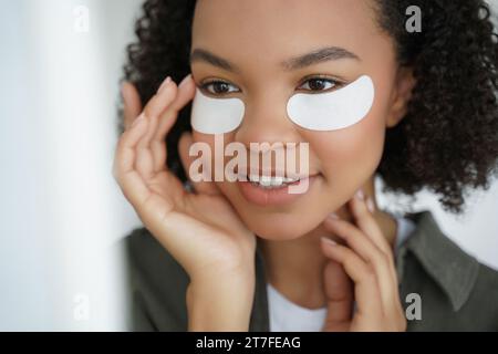 Schwarze Frau mit unter-Augen-Behandlungspflastern, die sich auf Hautpflege-Schönheit konzentrieren Stockfoto