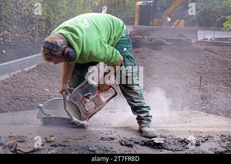 Garten-Landschaftsbau ein Garten- und Landschaftsbaubetrieb bereitet eine Fläche für den Bau einer Zufahrt vor. Mit einer Benzinflex werden gerade Kanten am alten Untergrund geschnitten. Quelle: Imago/Alamy Live News Stockfoto