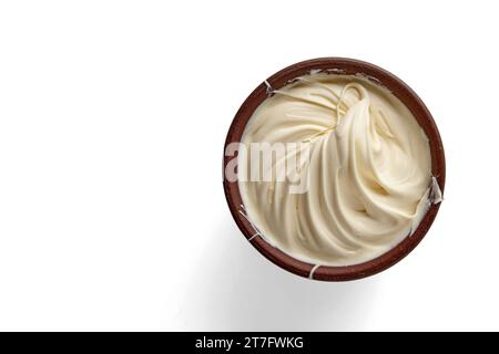 Butter wurde in einer braunen Tonschale auf einem Hintergrund in eine Spirale geschlagen und verdreht. Draufsicht mit Kopierbereich Stockfoto