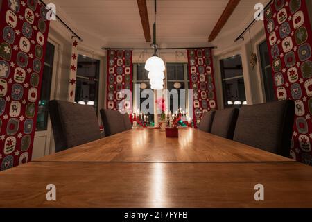 Weihnachtlich dekorierter Speisesaal mit Tisch für Heiligabend. Lichter, Vorhänge, kleine Weihnachtsmannfiguren Stockfoto