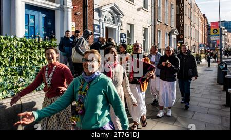 Gruppe von Hare Keishna, fröhlich singend und spielend Musikinstrumente während einer Dubliner Straßenprozession. Stockfoto