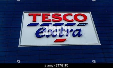 Tesco Extra Store-Schild an einer dunkelblauen gefliesten Wand mit auffälligem rot-blauem Branding auf weißem Hintergrund, das den britischen Supermarkt ch repräsentiert Stockfoto