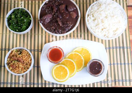 Traditionelles brasilianisches Essen Feijoada mit Bohnen, Schweinefleisch, Speck, Wurst mit Kohl, Reis, Salat, Gewürze und Pfeffer. Rustikale Küche. Stockfoto