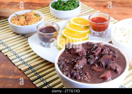 Köstliches brasilianisches Essen Feijoada mit Bohnen, Schweinefleisch, Speck, Wurst mit Kohl, Reis, Salat, Gewürze und Pfeffer. Rustikale Küche Stockfoto