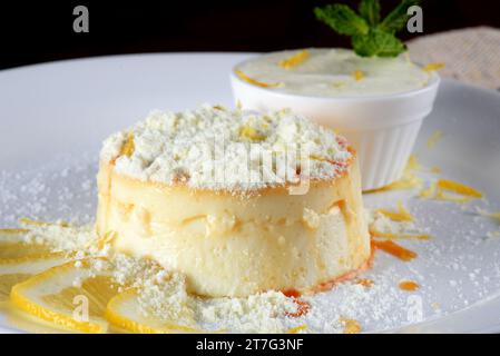 Kondensmilch und Eigelb Pudding mit köstlichem Sirup, der mit Frischkäse und hausgemachter Pulvermilch tropft. Kaffeekanne und kleine Töpfe mit Zucker, Bu Stockfoto