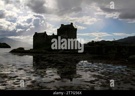 Silhouetten von eilean donan Castle in schottland mit Blick auf den Fluss und den Sonnenuntergang. Stockfoto