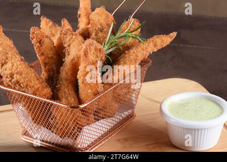 Köstliche Stücke von gebratenem Fisch und Hühnchen paniert mit Panko Mehl serviert mit Kräutersoße und Kabeljau. Stockfoto