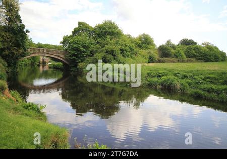 der fluss führt durch die Brücke im Pollok Park in Glasgow mit Wolken und Bäumen, die sich im Wasser spiegeln. Stockfoto