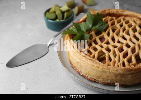 Frisch gebackener Rhabarberkuchen und Tortenheber auf hellgrauem Tisch, Nahaufnahme Stockfoto