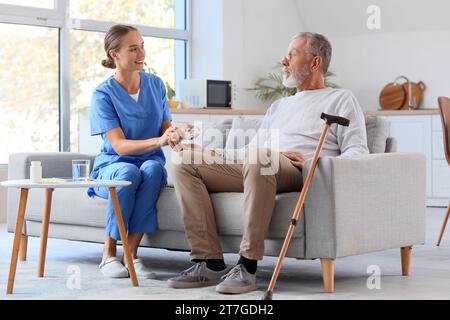 Senior-Mann mit Krankenschwester, die Pille zu Hause nimmt Stockfoto