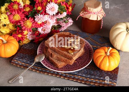 Teller Toast mit süßer Kürbismarmelade und Samen auf grauem Tisch Stockfoto