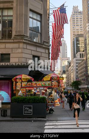 Eine Frau, die die Straße vor Saks auf der Fifth Avenue überquert Stockfoto