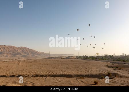 Gruppe von Heißluftballons, die in der trockenen Wüstenlandschaft des Tals der Könige abheben Stockfoto