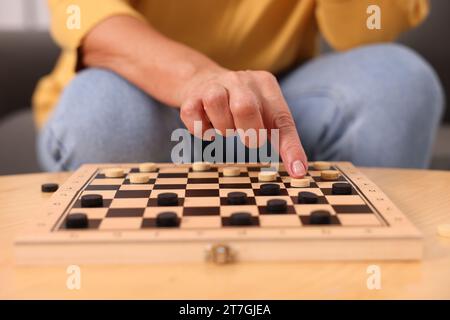 Frau, die Schachfiguren am Holztisch spielt, Nahaufnahme Stockfoto