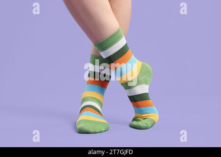 Frau in stilvollen bunten Socken auf violettem Hintergrund, Nahaufnahme Stockfoto