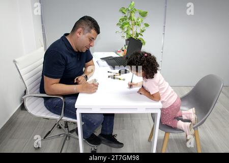 3-jährige brünette, lockige Lateinfrau zeichnet als Therapie für Autismus und ADHS mit Psychoanalytiker-Therapeutin Stockfoto
