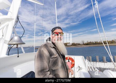 Captain der Fähre zwischen Bronx City Island und Hart Island Phil Tobin, der während der Pressevorschau der öffentlichen Touren auf der Insel, die von den Rangern des NYC Parks Department in New York am 15. November 2023 durchgeführt wurden, gesehen wurde. Jahrhundertelang wurde Hart Island als öffentlicher Friedhof genutzt, um Leichen von Menschen zu begraben, die nicht beansprucht wurden, insbesondere während Epidemien und Pandemien. Einige Teile wurden von der Justizbehörde als Teil des Gefängnissystems verwendet. Die Insel wurde für psychische Patienten genutzt, um Menschen zu unterbringen, die sich von Infektionserkrankungen erholten. In den letzten Jahren wurde es umfangreich modernisiert und war tr Stockfoto