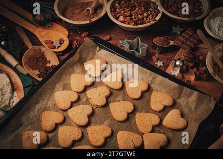 Auf einem Blech gebackene herzförmige Kekse, Backzutaten, Mehl, Zucker, Mandeln, Nüsse, Schokolade, Zimt, Keksschneider Stockfoto