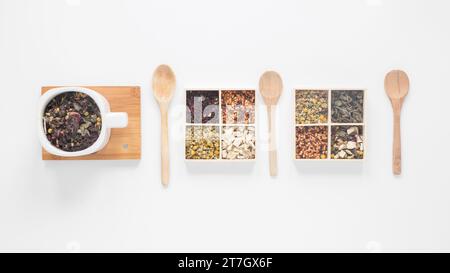 Dry tea leaves herbs wooden spoon arranged row white background Stockfoto