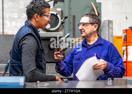 Metallfabrikarbeiter aus dem Bereich der numerischen Kontrolle sprechen Stockfoto