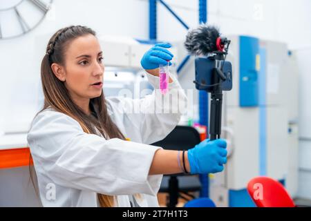 Wissenschaftler zeigen Proben, während sie ein Video aufnehmen, während sie ein mobiles Gerät im Labor aufnimmt Stockfoto