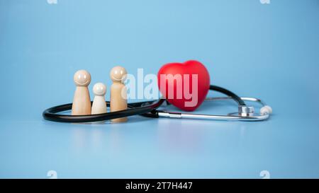 Konzept der Krankenversicherung und der medizinischen Wohlfahrt, Holzpuppe und rotes Herz mit Stethoskop auf blauem Hintergrund, Krankenversicherung und Zugang zu Gesundheit Stockfoto