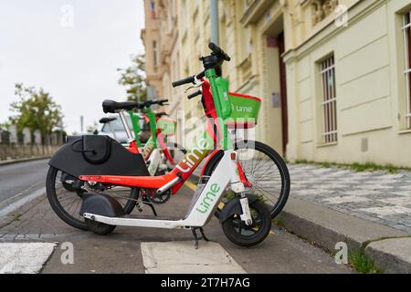 Geparkter E-Roller und Fahrrad der Firma Lime am Straßenrand im Stadtzentrum von Prag in der Tschechischen Republik Stockfoto