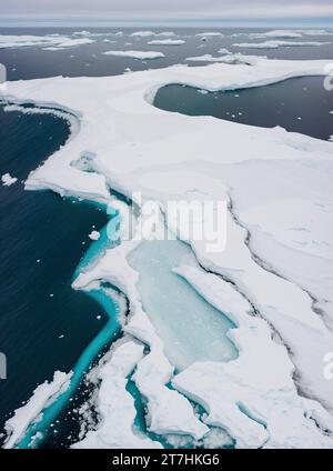 Eine majestätische Landschaft mit schneebedeckten Bergen und eisigem Wasser, mit mehreren schwimmenden Eisbergen, die über die gesamte Szene verteilt sind Stockfoto