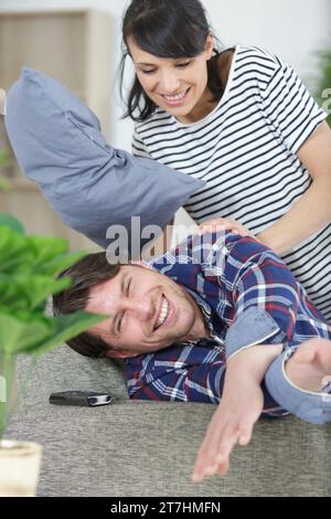 Ein Paar auf dem Sofa, das einen Kissenkampf hat Stockfoto