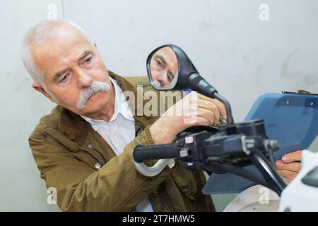 Ein älterer Mann sitzt im Showroom auf dem Roller Stockfoto