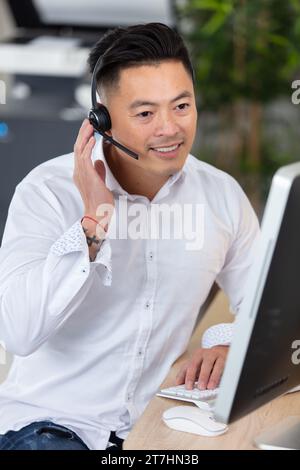 Gutaussehender Berater der asiatischen Hotline, der ein Headset trägt Stockfoto