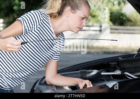 Die Frau überprüft das Öl im Motor des Autos Stockfoto