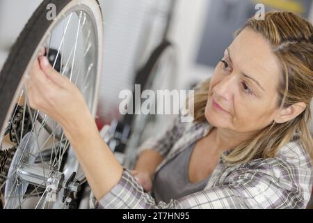 Reife Frau, die Räder von Fahrrädern in der Werkstatt repariert Stockfoto