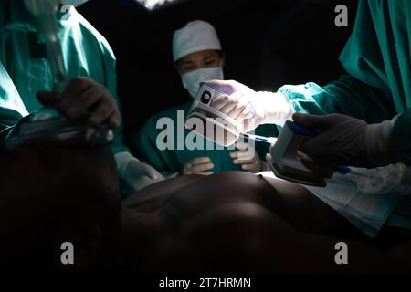 Diverse Chirurgen mit Operationskittel mit Defibrillator im Operationssaal im Krankenhaus Stockfoto