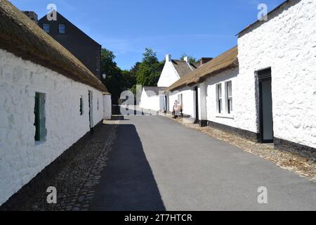 Cultra, County Down, Nordirland, 15. Juni 2014 - Village Street im Ulster Folk and Transport Museum mit zwei Männern, die sich auf der Fensterbank unterhalten Stockfoto