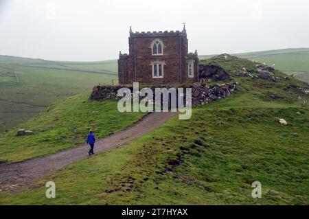 Frau geht zum Doyden Castle am Doydon Point A Rocky Headland in der Nähe von Port Quin am South West Coastal Path in Cornwall, England. UK Stockfoto