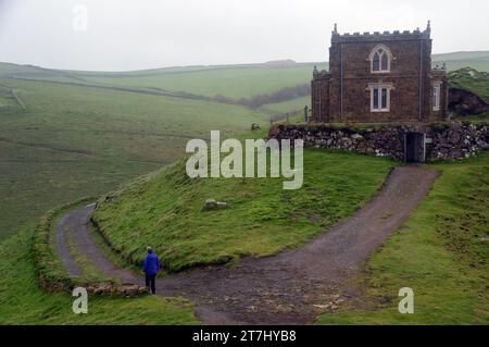 Frau, die von Doyden Castle am Doydon Point A Rocky Headland in der Nähe von Port Quin am South West Coastal Path in Cornwall, England, läuft. UK Stockfoto