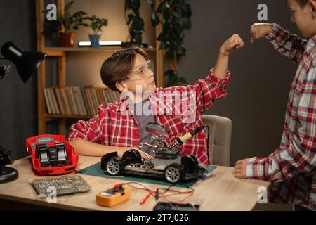 Junge Jungen bauen Roboter und Autos, verwenden Lötkolben, um Chips und Drähte zu Hause zu verbinden. Erfindungen und Kreativität für Kinder Stockfoto