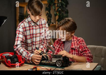 Teenager-Brüder studieren Elektronik und bauen ein Auto auf der Fernbedienung in ihrem Zimmer, arbeiten an einem Wissenschaftsprojekt Stockfoto