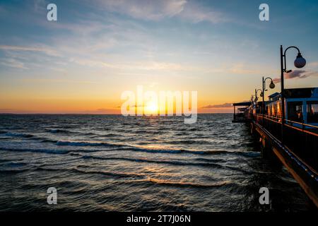 Pier am Strand in der Nähe von Misdroy in Polen. Natürlicher Küstenabschnitt an der polnischen Ostsee. Landschaft am Meer mit Sonnenuntergang am Pier. Stockfoto