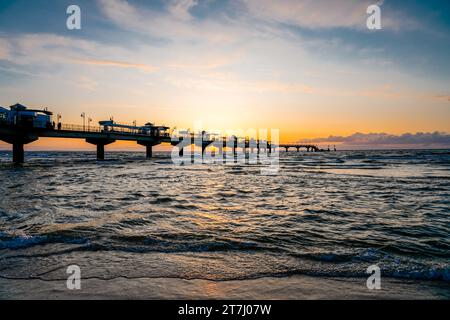 Pier am Strand in der Nähe von Misdroy in Polen. Natürlicher Küstenabschnitt an der polnischen Ostsee. Landschaft am Meer mit Sonnenuntergang am Pier. Stockfoto