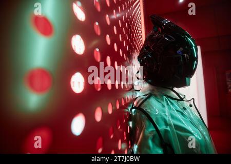 Futuristisches Seitenporträt einer Person mit schwarzer Robotermaske gegen Rot, Kopierraum Stockfoto