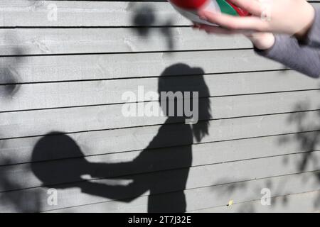 Teenager hält Volleyball mit ihrem Schatten auf grauem Holzhintergrund Stockfoto