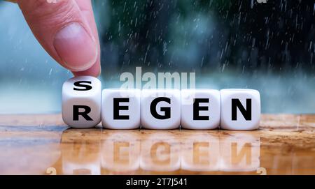 Die Hand würfelt und ändert das deutsche Wort Regen in Segen. Stockfoto