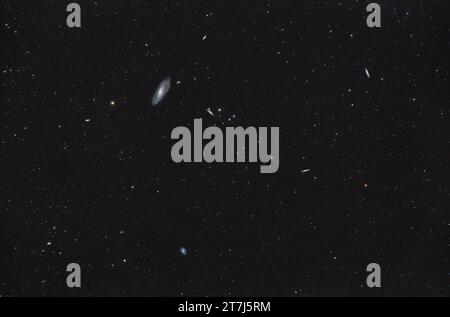 Es handelt sich um einen Rahmen der Helikopter-Spiralgalaxie M106 oben, mit einer Reihe ihrer Gefährten und nahe gelegenen Galaxien in Canes Venatici. Die Kante an Stockfoto