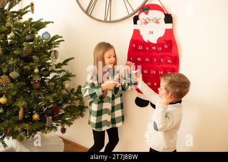 Der Bruder und die Schwester fanden Geschenke im Adventskalender des weihnachtsmanns Stockfoto