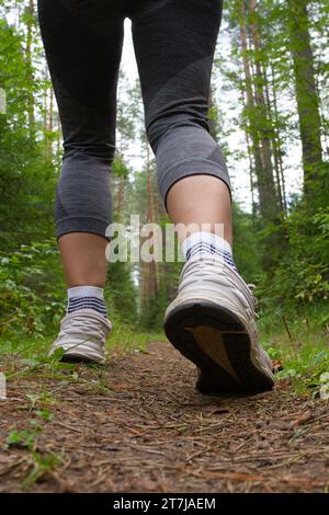 Beine einer Läuferin auf einem Waldweg beim Joggen Stockfoto