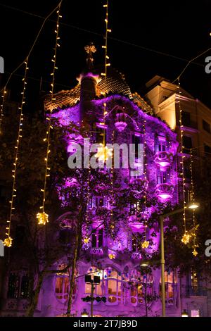 Casa Batlló ist in violetten Tönen getaucht und mit zauberhaften Weihnachtslichtern geschmückt, die die lebhafte Straße darunter mit einem festlichen Leuchten erstrahlen lassen und einen Zauber schaffen Stockfoto