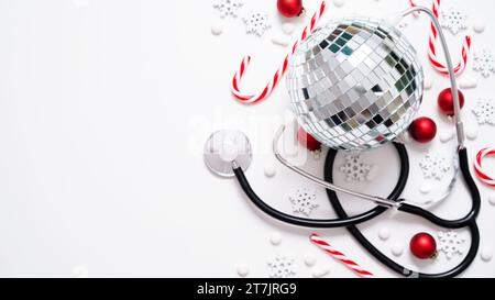 Weihnachten medizinische Banner.Close-up von Stethoskop, Discoball, gestreifte Lutscher, rote Kugeln, Sterne und Pillen auf weißem Hintergrund, Ansicht von oben, flache Lage, Kopie Spa Stockfoto